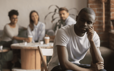 A man seated on a chair addresses a group of attentive individuals gathered around him.