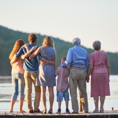 A family stands together on a dock, admiring the peaceful water in front of them.