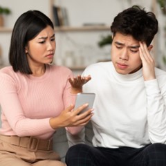 A man and woman are closely examining a smartphone together, sharing a moment of interest and engagement.