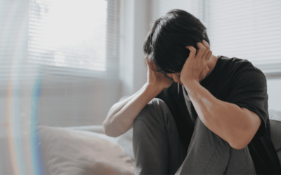 A man sits on a couch, his head resting in his hands, conveying a sense of distress or deep contemplation.