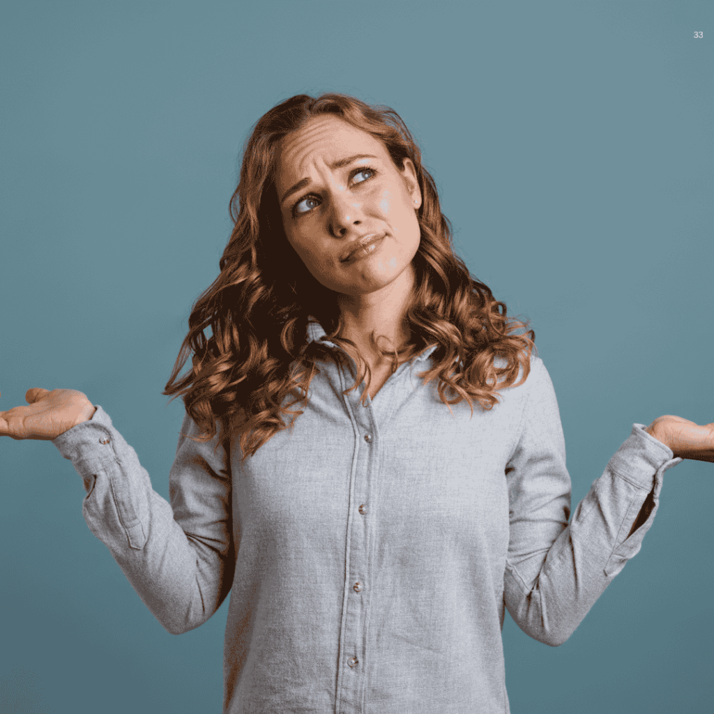 a young woman with long curly hair shrugging with both hands raised and a puzzled expression